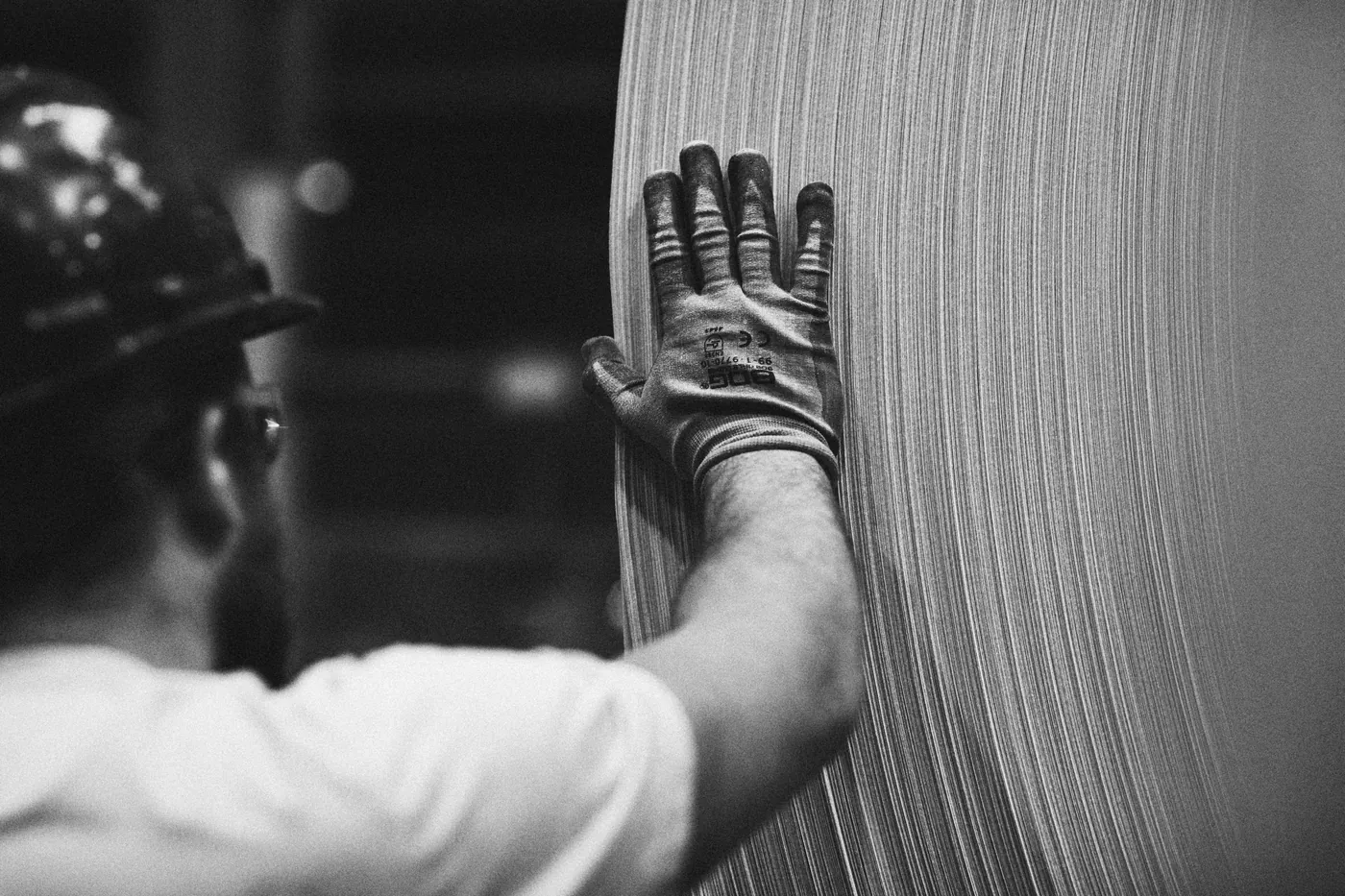 A gloved hand resting on the edge of a steel coil