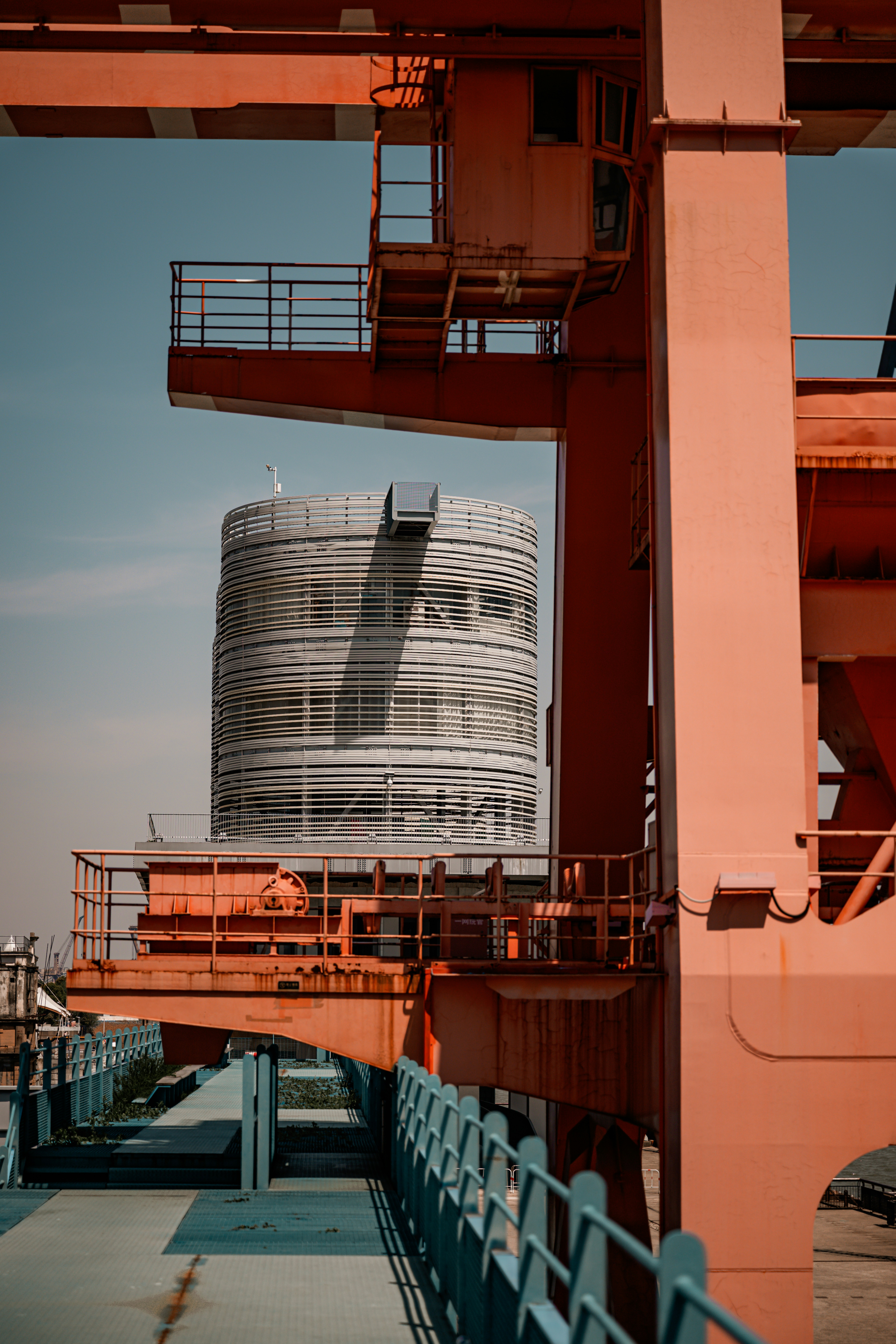 Gantry crane over a silver drum tower at an industrial plant