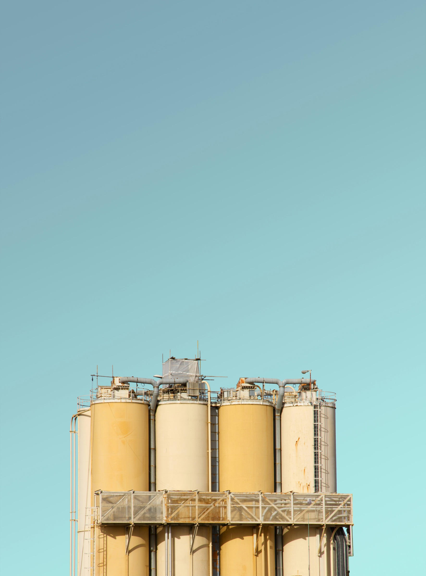 Cream silos and piping against a flat sky