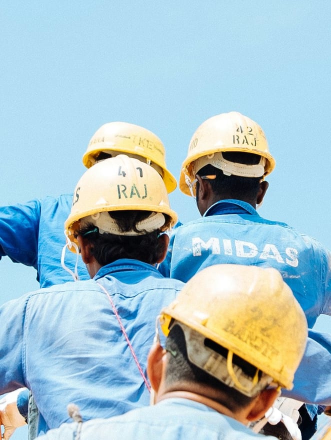 Four workers in hard hats seen from below against a clear sky