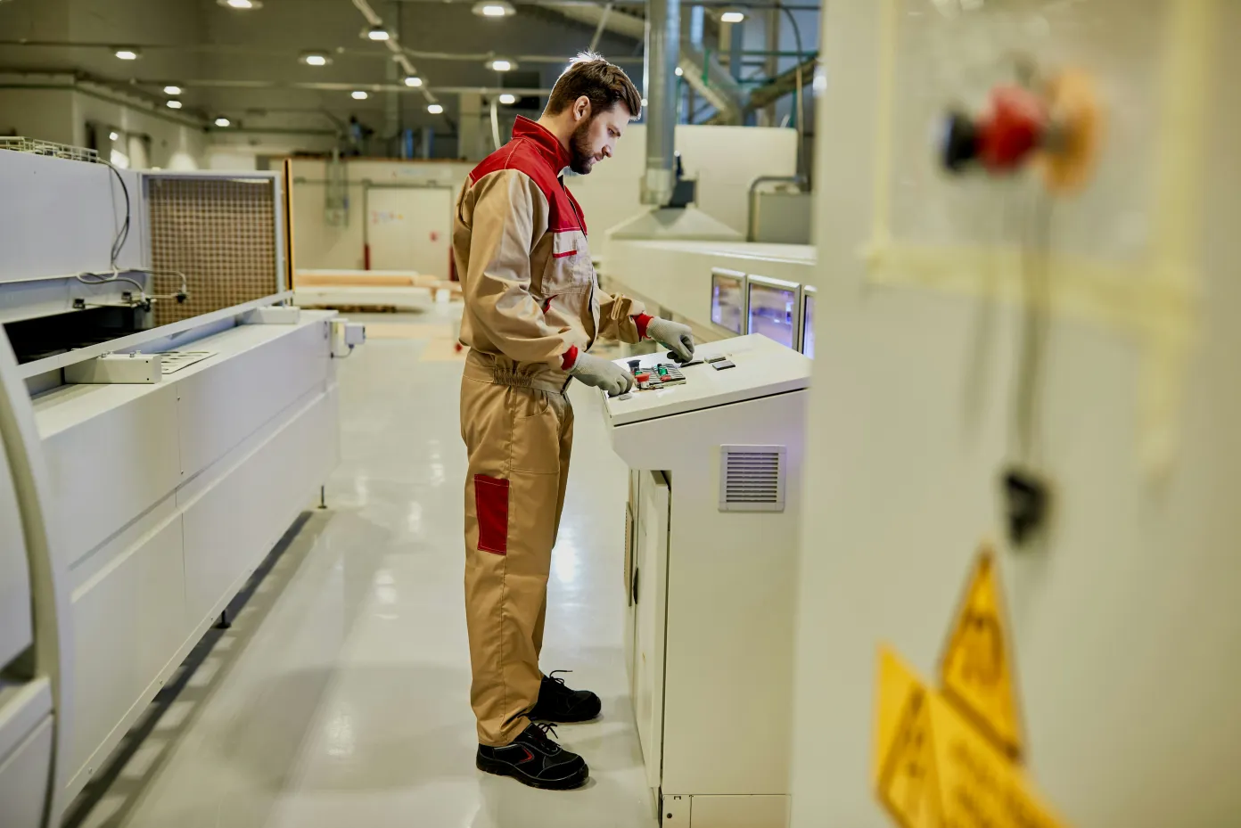 An operator working a machine control panel on the shop floor